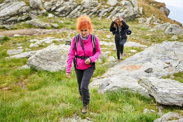 两个背着背包在山路上徒步旅行的妇女 — 图库照片