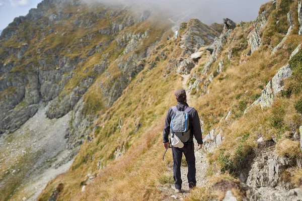 背着背包在山路上徒步旅行的人 — 图库照片