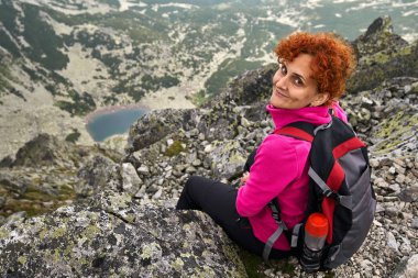 Sırt çantalı gezgin kadın dağlarda bir buzul gölünün üstünde