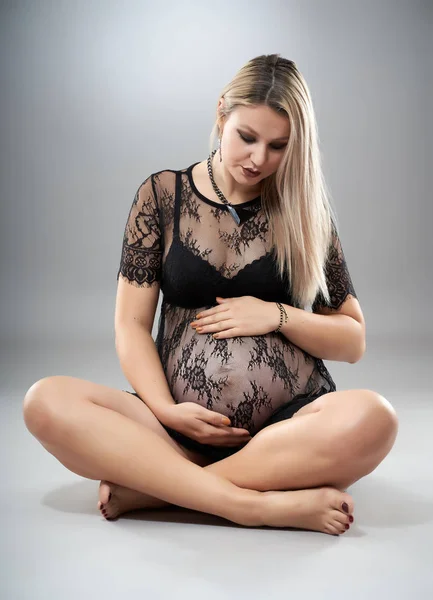 スタジオポートレートの美しいです妊娠中の女性で黒服の横にあるグレーのスタジオの背景 — ストック写真