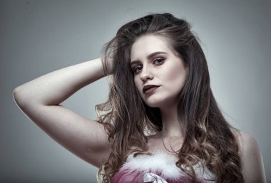 Gri arka planda stüdyo çekimi olan güzel bir genç kadının yakın çekimi.