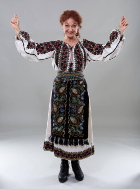 Gri arka planda geleneksel kostümlü olgun Romen kadın