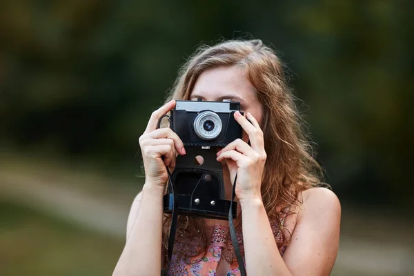 屋外で写真を撮るヴィンテージフィルムカメラを持つ女性写真家 — ストック写真