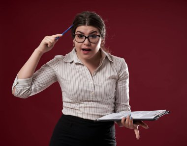 Gözlüklü ve panosu olan bir iş kadını, ne yapacağından emin değil.