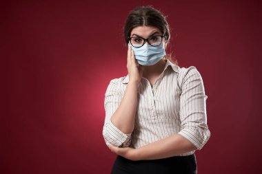 Yüzünde şüphe ifadesi olan koruyucu maskeli bir iş kadını.