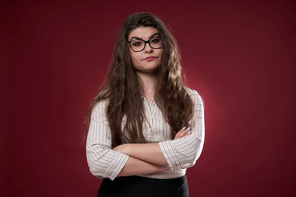 Misstrauische Junge Geschäftsfrau Mit Brille Vor Rotem Hintergrund — Stockfoto