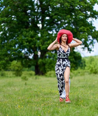 Yazlık elbisesiyle bir meşe ormanında poz veren muhteşem güzellik mankeni.