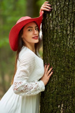 Yazlık elbisesiyle bir meşe ormanında poz veren muhteşem güzellik mankeni.