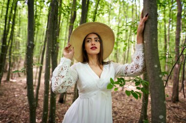 Yazlık elbisesiyle bir meşe ormanında poz veren muhteşem güzellik mankeni.