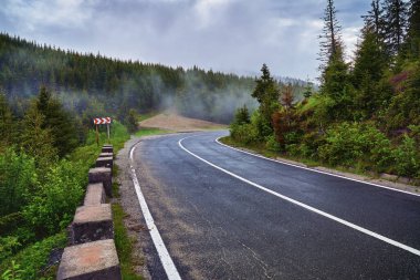 Asfalt yolu sislerin arasından dağlara çıkıyor.