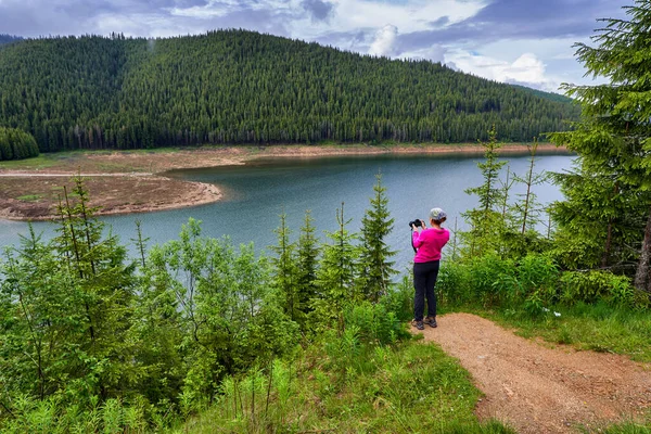 Женщина Туристка Камерой Фотографирующая Озеро Между Горами — стоковое фото
