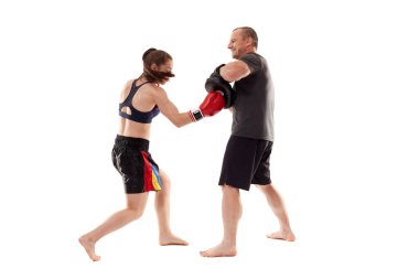 Kız kickboks dövüşçüsü koçuyla yumruk tokuşturuyor, beyaz arka planda izole edilmiş.