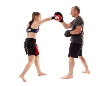 Kız kickboks dövüşçüsü koçuyla yumruk tokuşturuyor, beyaz arka planda izole edilmiş.