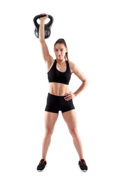 Genç atletik kadın beyaz arka planda yalnız başına kettlebell ile egzersiz yapıyor.