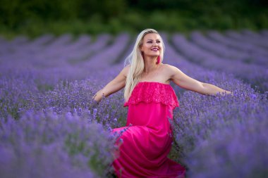Lavanta tarlasında çeşitli pozlarda pembe elbiseli genç sarışın kadın.