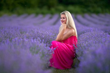 Lavanta tarlasında çeşitli pozlarda pembe elbiseli genç sarışın kadın.