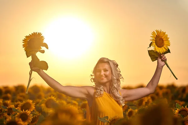 Beautiful blonde Caucasian woman in a sunflower field at sunset