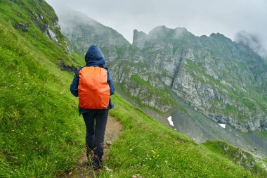 Sırt çantalı bir turist dağlarda yürüyüş yapıyor.