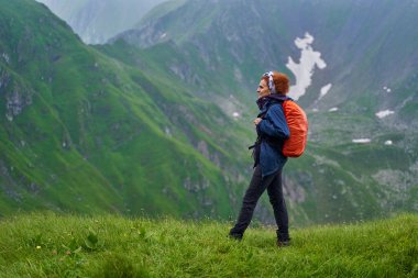Sırt çantalı bir turist dağlarda yürüyüş yapıyor.