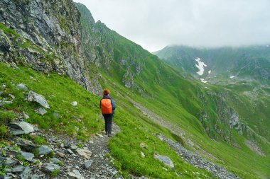 Sırt çantalı bir turist dağlarda yürüyüş yapıyor.