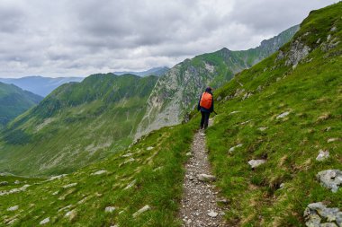 Yağmurlu bir yaz gününde dağ yolunda kadın yürüyüşçüyüm.