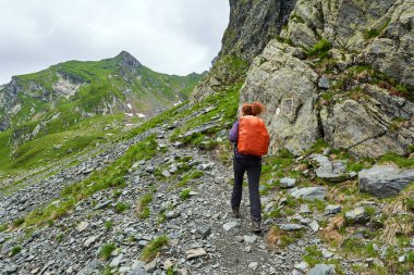 Sırt çantalı bir turist dağlarda yürüyüş yapıyor.