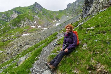 Sırt çantalı bir kadın uzun bir yoldan sonra dinleniyor.