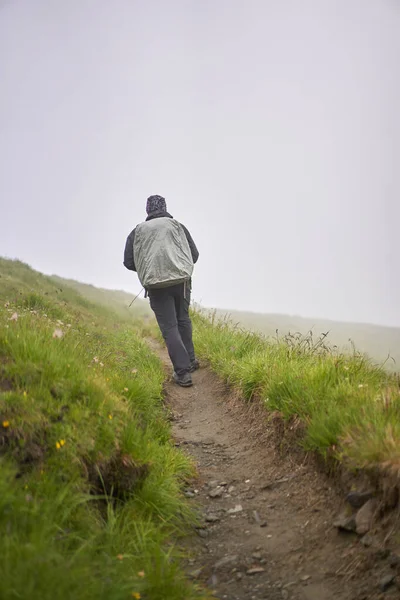 带着雨衣和大背包的远足者徒步旅行到高地 — 图库照片