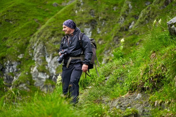 带着雨衣和大背包的远足者徒步旅行到高地 — 图库照片
