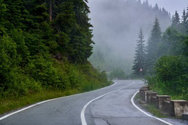 Asfalt yolu sislerin arasından dağlara çıkıyor.
