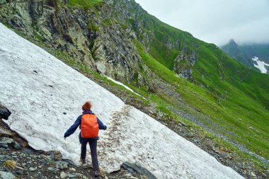 Sırt çantalı bir turist dağlarda yürüyüş yapıyor.