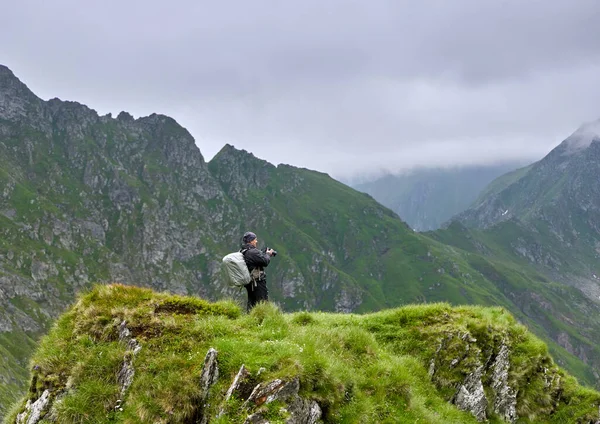专业的自然摄影师 带着相机和大背包远足到高地 — 图库照片