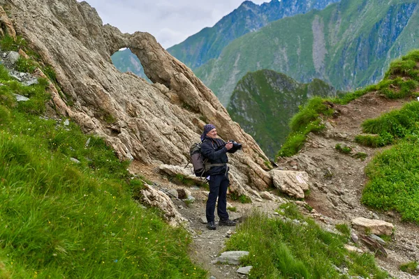 专业的自然摄影师 带着相机和大背包远足到高地 — 图库照片