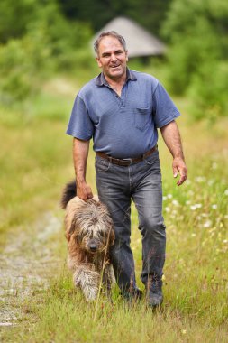 Dışarıda oynayan büyük çoban köpeği olan olgun bir adam.