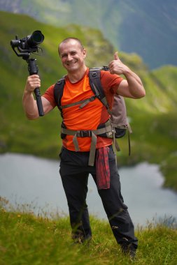 Profesyonel kameraman dağların tepesinde bir vibratörle çekim yapıyor.