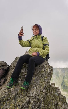 Sırt çantalı, dağda bir patikada kıdemli beyaz kadın yürüyüşçü.