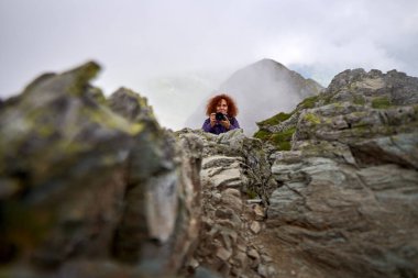 Sırt çantası ve kamerasıyla dağda gezen profesyonel fotoğrafçı kadın.