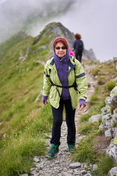 山の中の歩道にバックパックを持つシニア白人女性ハイカー — ストック写真