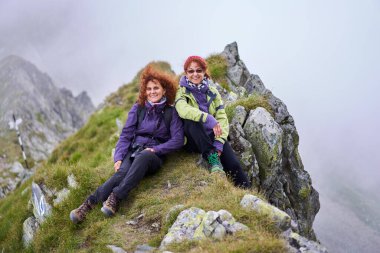 Sırt çantalı iki arkadaş dağda yürüyüş yapıyor.