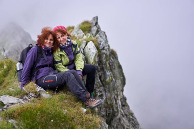 Sırt çantalı iki arkadaş dağda yürüyüş yapıyor.