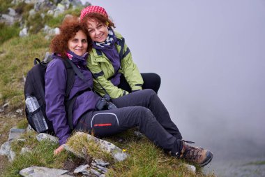 Sırt çantalı iki arkadaş dağda yürüyüş yapıyor.