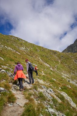 Dağlara doğru dik bir yola tırmanan dağcı ailesi.