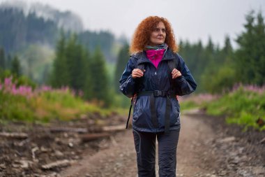 Sırt çantalı Kafkas kadın yağmurlu bir günde dağlarda yürüyüş yapıyor.