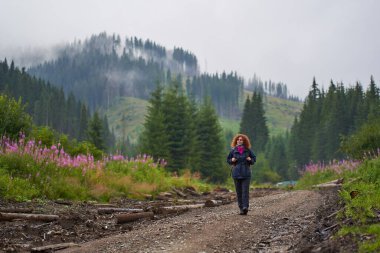 Sırt çantalı Kafkas kadın yağmurlu bir günde dağlarda yürüyüş yapıyor.