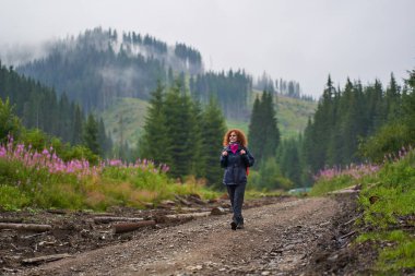 Sırt çantalı Kafkas kadın yağmurlu bir günde dağlarda yürüyüş yapıyor.