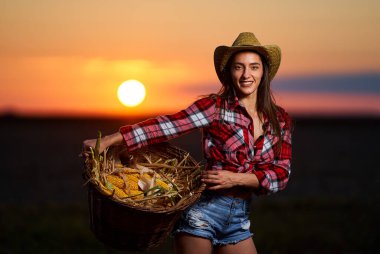 Mısır hasadında şapkalı ve ekose gömlekli güzel çiftçi kadın.