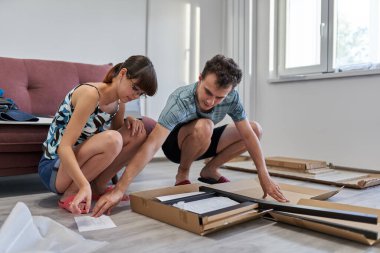 Yeni evlerinde mobilya montajı yapan genç bir çift.