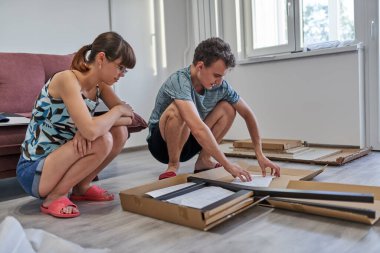 Yeni evlerinde mobilya montajı yapan genç bir çift.