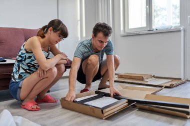 Yeni evlerinde mobilya montajı yapan genç bir çift.