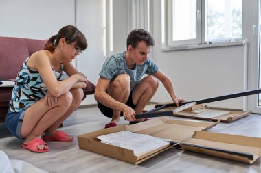 Yeni evlerinde mobilya montajı yapan genç bir çift.